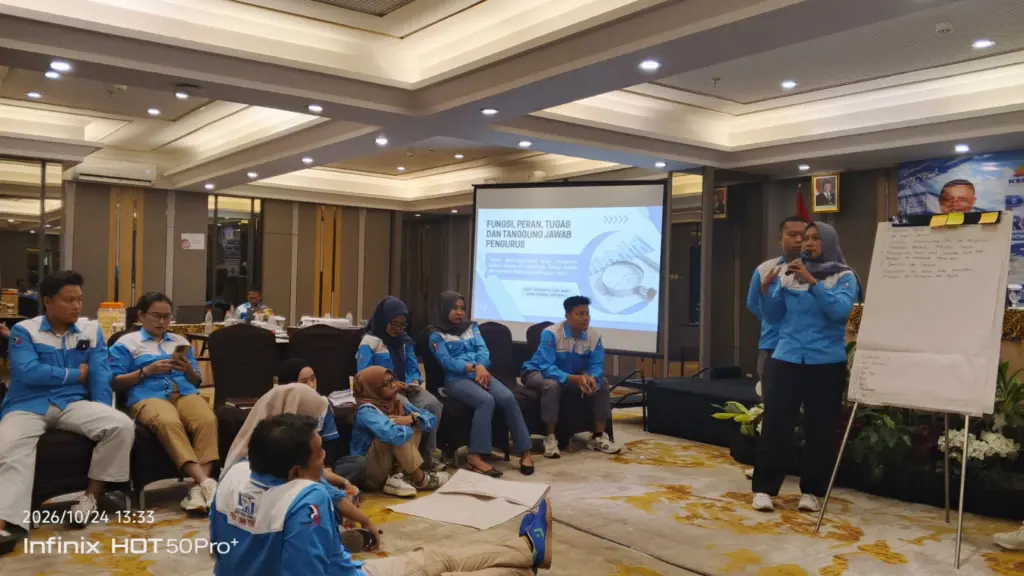 Peserta perempuan berseragam SPN presentasi di samping papan flipchart